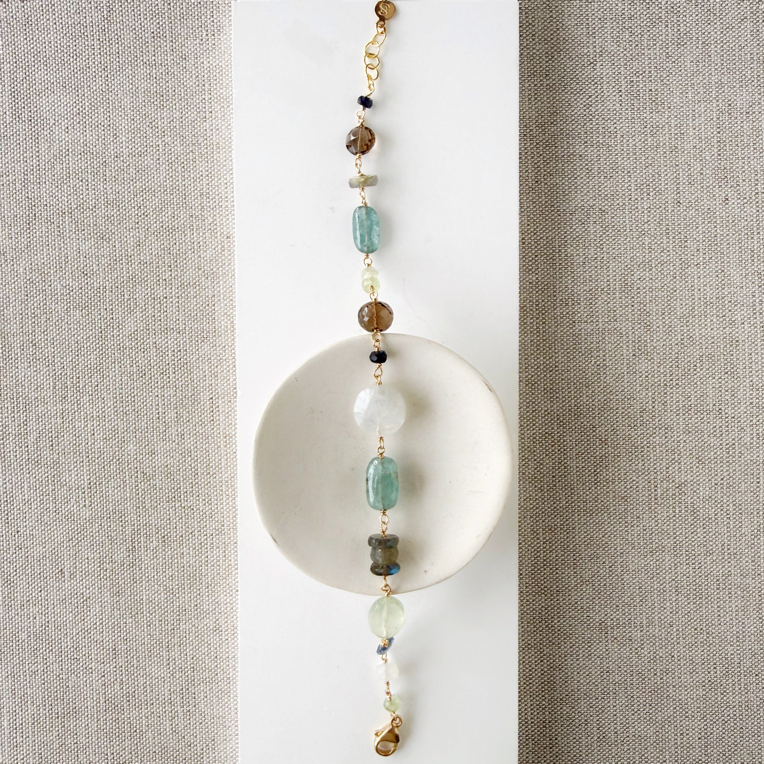 Multicolored chunky gemstone bracelet on a white square card with a textured beige background