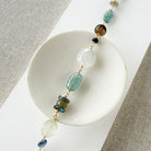 Multicolored chunky gemstone bracelet on a white square card with a textured beige background