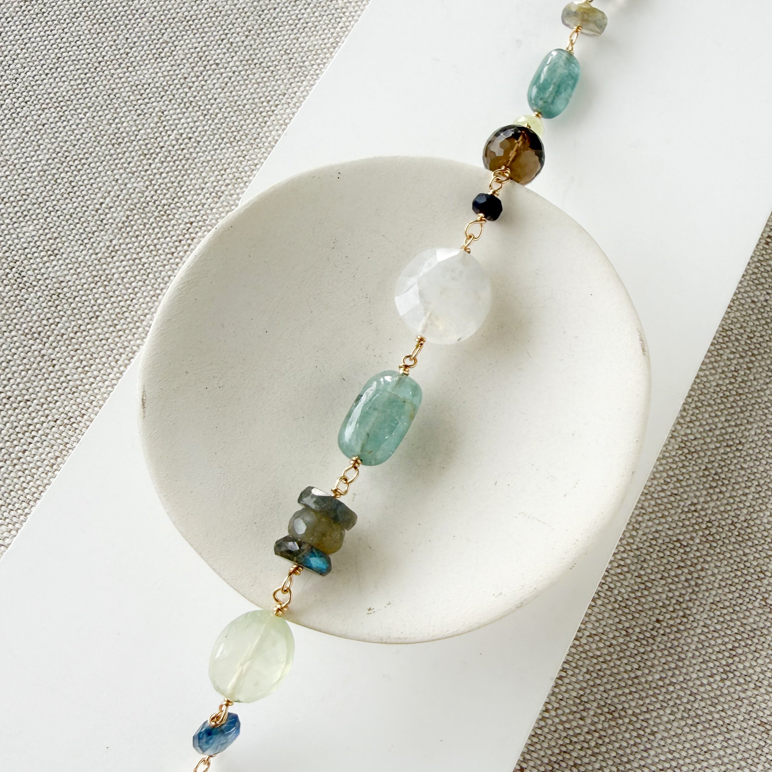 Multicolored chunky gemstone bracelet on a white square card with a textured beige background