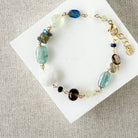 Multicolored chunky gemstone bracelet on a white square card with a textured beige background