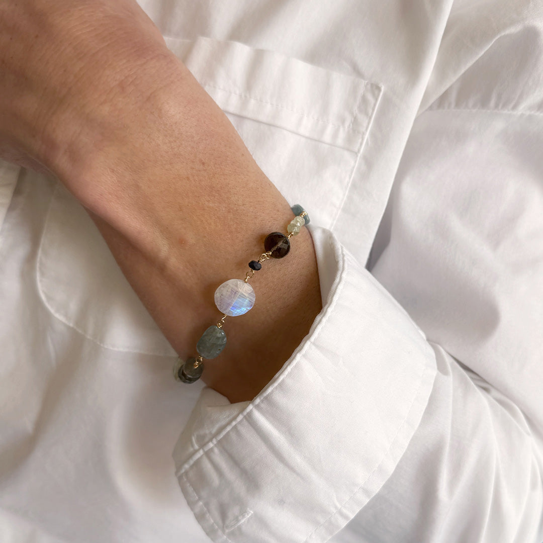 Person wearing a bracelet with gemstones stones in a white shirt