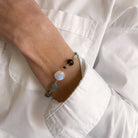 Person wearing a bracelet with gemstones stones in a white shirt