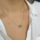 Gold necklace with a moth pendant worn by a person in a white shirt.