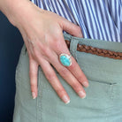 Close up of woman wearing Nevada turquoise ring against a blue background