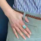 Close up of woman wearing Nevada turquoise ring against a blue background