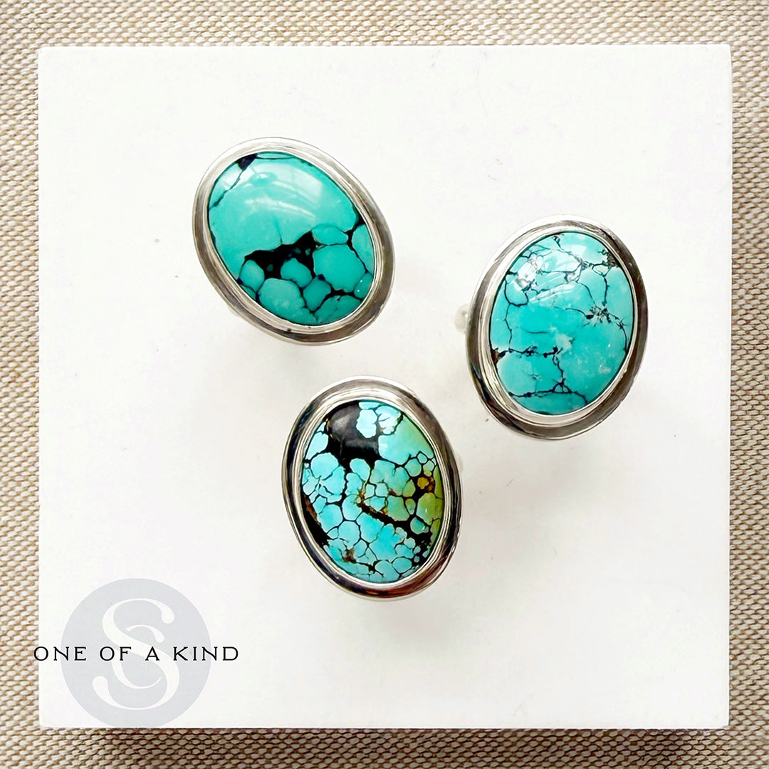 Nevada turquoise rings on a white card with 'One of a Kind' branding.