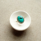 White ceramic dish with a Nevada turquoise ring on a beige fabric background