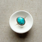White ceramic dish with a Nevada turquoise ring on a beige fabric background