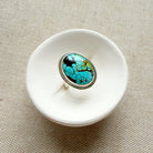 White ceramic dish with a Nevada turquoise ring on a beige fabric background