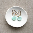Pair of earrings with blue chalcedony stones on a white dish against a beige background