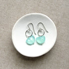 Pair of earrings with blue chalcedony stones on a white dish.