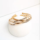 Set of gold bracelets with inscriptions on a white surface