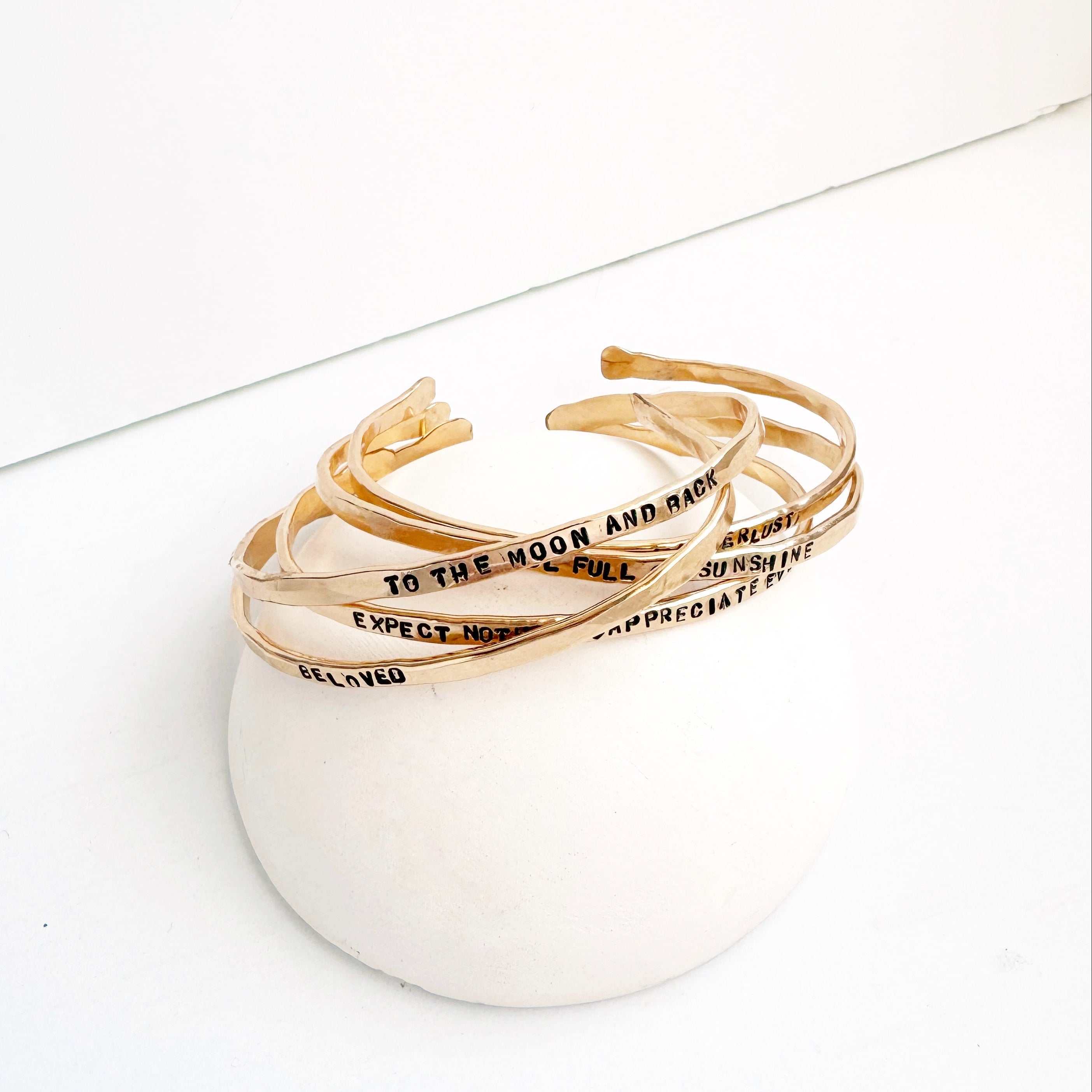 Set of gold bracelets with inscriptions on a white surface