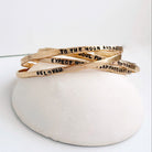 Set of gold bracelets with motivational phrases on a white surface