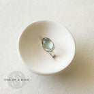 Oval aquamarine mixed metal ring in a white dish with one of a kind icon