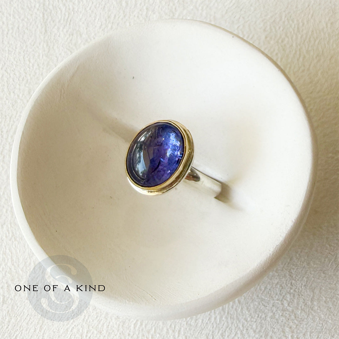 Ring with a purple tanzanite gemstone on a white dish, with 'One of a Kind' icon.