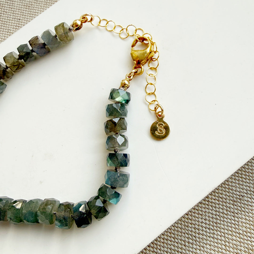 Clasp detail of labradorite knotted necklace with faceted gemstones on a white plate