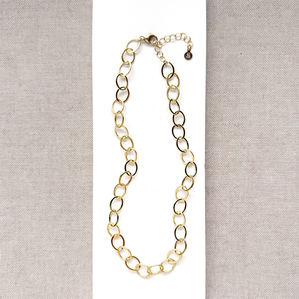 Chunky gold chain necklace on a white card with a gray background