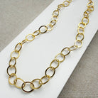 Chunky gold chain necklace on a white card with a gray background