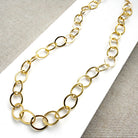 Chunky gold chain necklace on a white card with a gray background