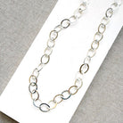 Chunky silver chain necklace on a white card with a gray background