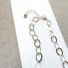 Chunky silver chain necklace on a white card with a gray background