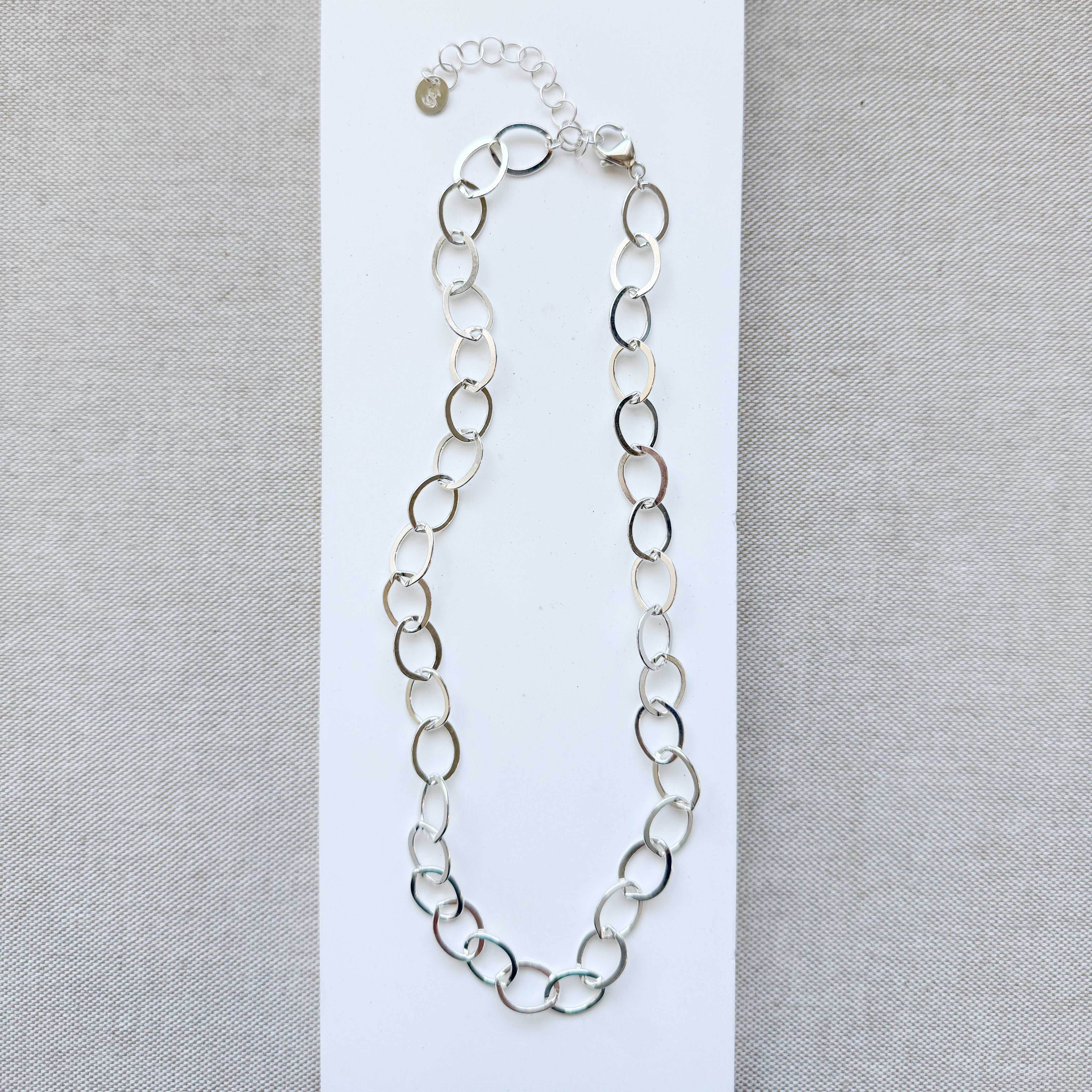 Chunky silver chain necklace on a gray background