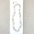 Chunky silver chain necklace on a white and beige fabric background