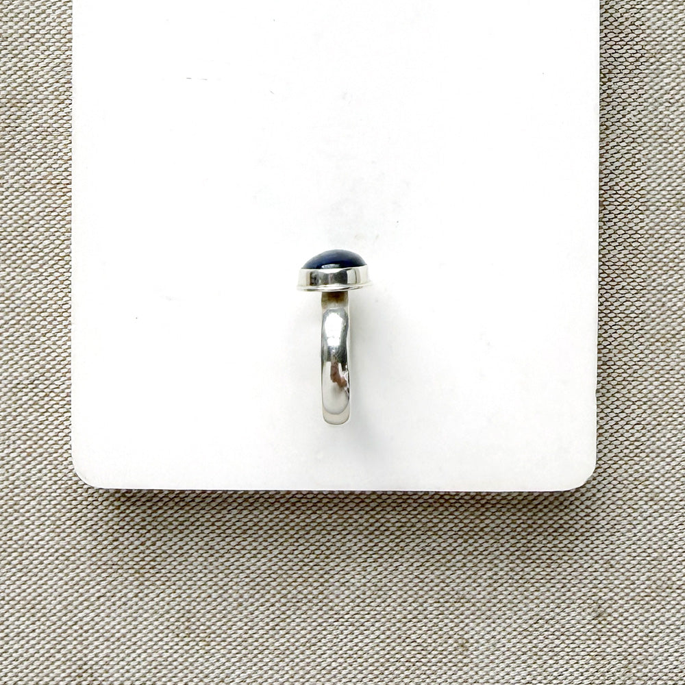 Oval shaped smooth blue kyanite mixed metal ring on a white dish