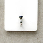 Oval shaped smooth blue kyanite mixed metal ring on a white dish