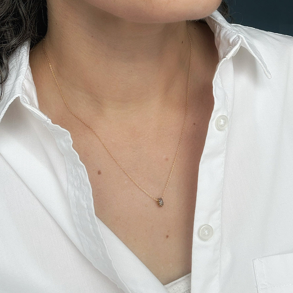 A close-up of a person wearing a gold necklace styled with a white button-down shirt.