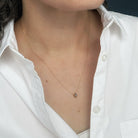 A close-up of a person wearing a gold necklace styled with a white button-down shirt.