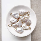 White dish filled with tear drop shaped pearl charms