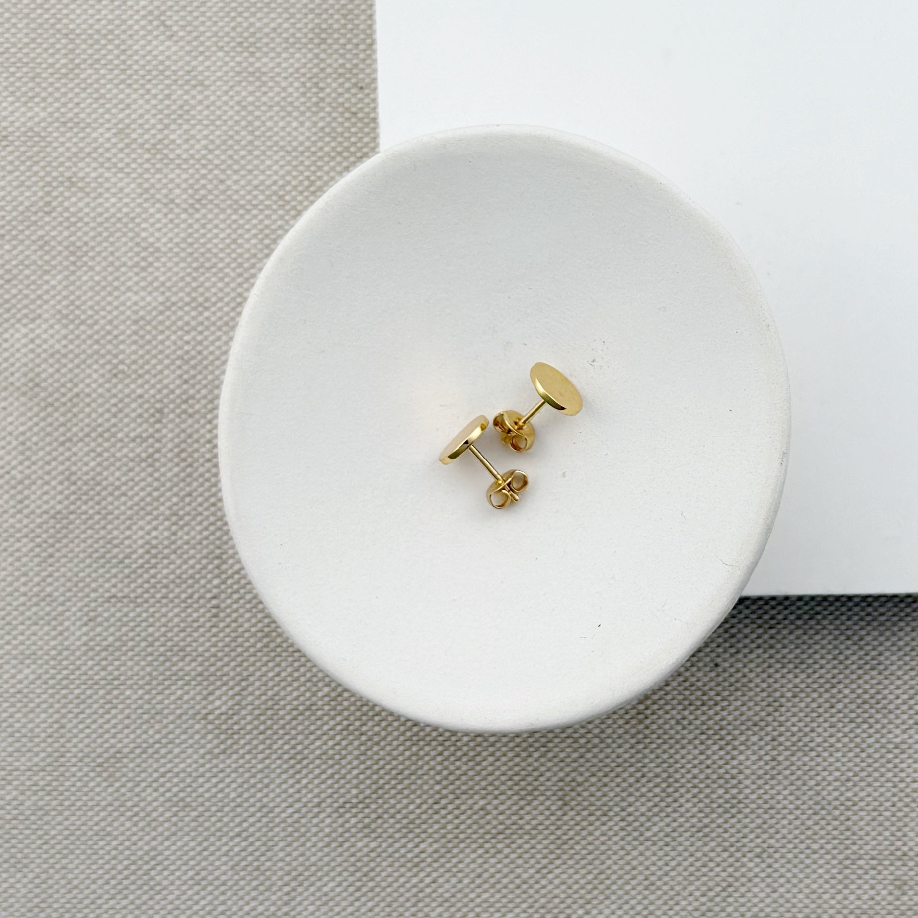 Small hammered disc studs in gold on a white dish