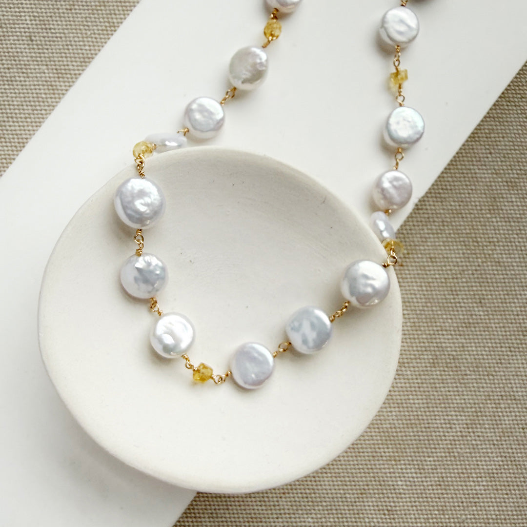 Coin pearl necklace with citrine gems in a white dish