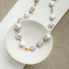 Coin pearl necklace with citrine gems in a white dish