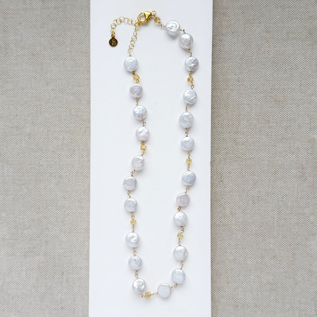 Coin pearl necklace with citrine gems on a white background