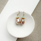 Pink pearl drop earrings in a white dish