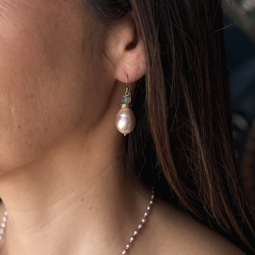 Close up of woman wearing pink pearl drop earring