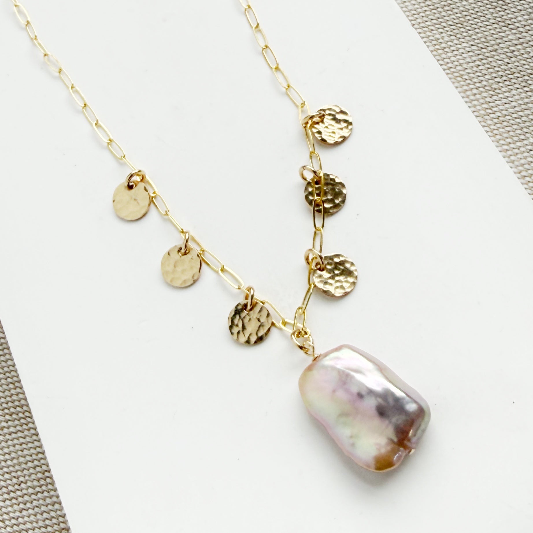 Close up of gold necklace with baroque pearl and gold discs