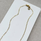Clasp detail of gold and baroque pearl necklace on a white tray