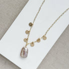 Close up of gold and baroque pearl necklace on a white tray