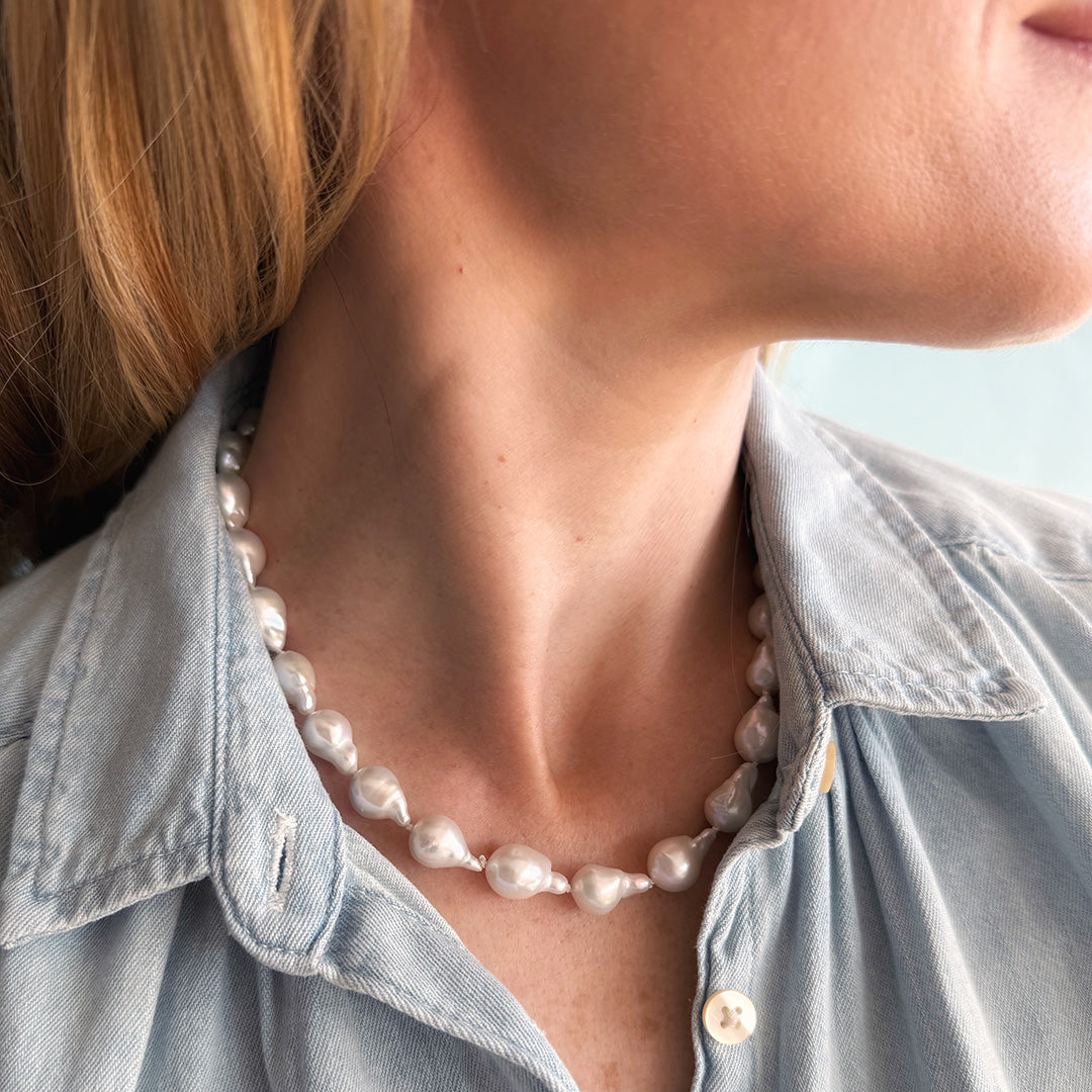 Pearl necklace worn by a person with a denim shirt