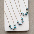 Three gold necklaces with Golden Hill turquoise beads on a white card against a beige background