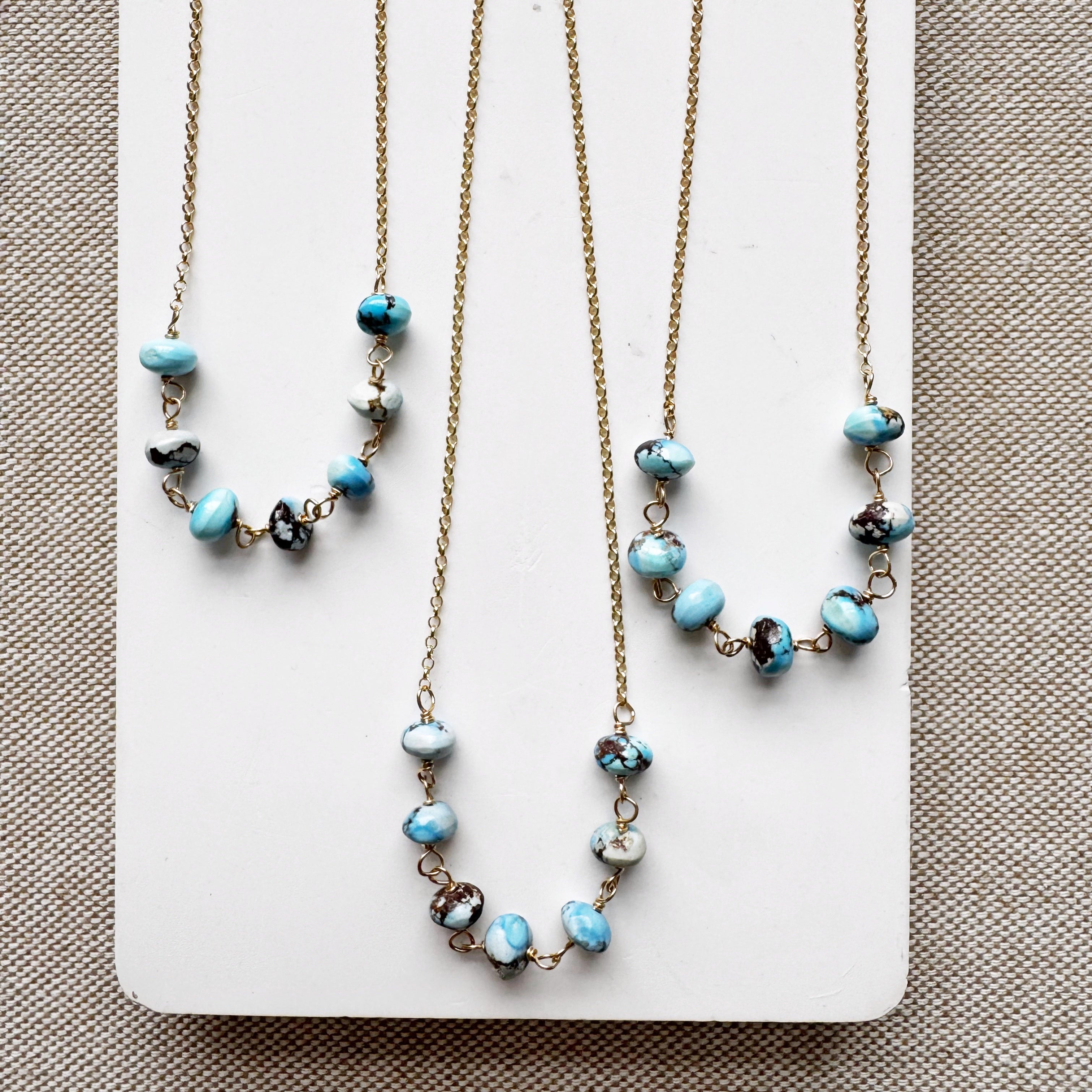 Necklaces featuring Golden Hill turquoise beads on a white card with a beige background