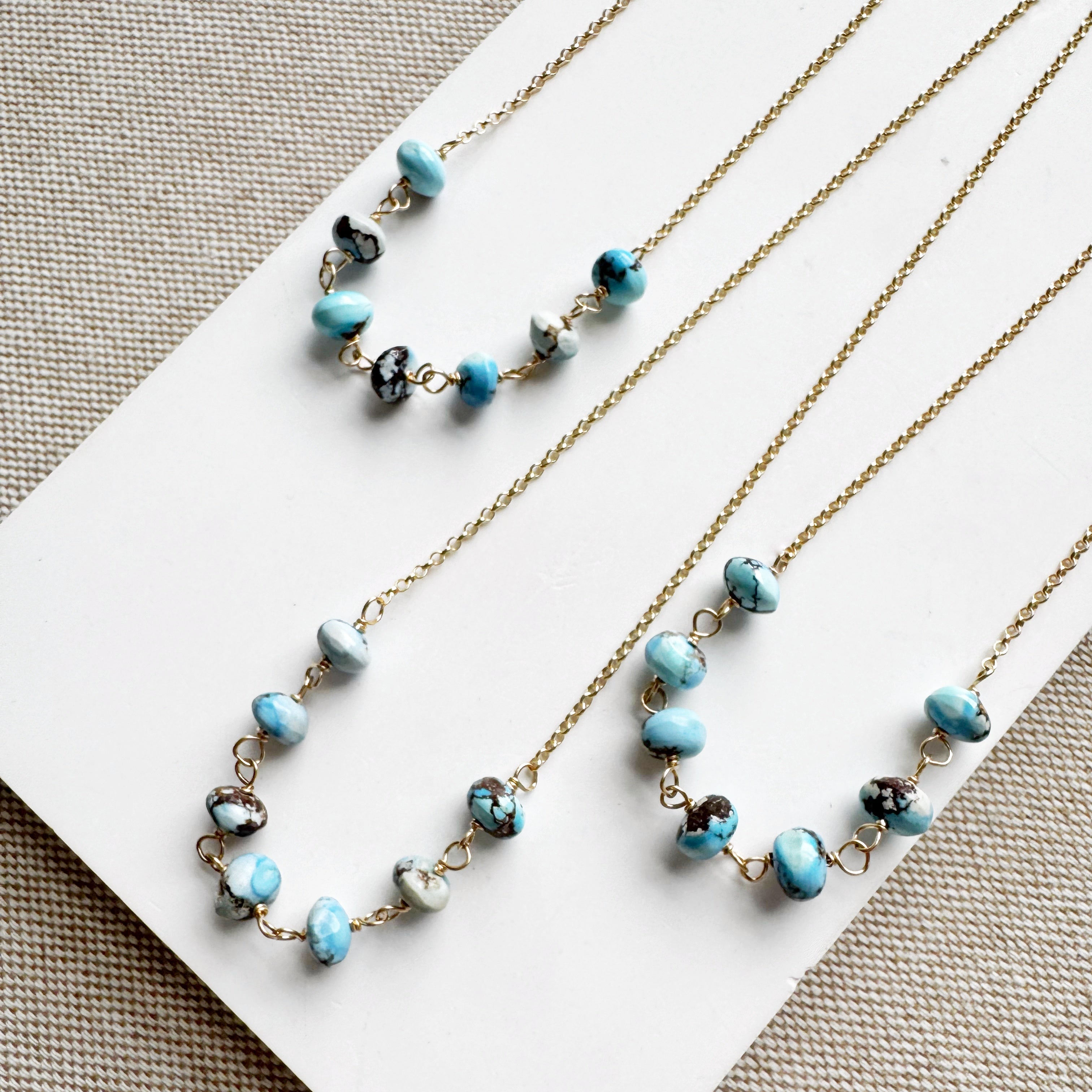 Necklaces featuring Golden Hill turquoise beads on a white card with a beige background