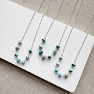 Silver chain necklaces in Golden Hill turquoise beads on a white card against a beige background