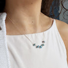 Gold necklace with small Golden Hill turquoise stones worn by a person in a white top