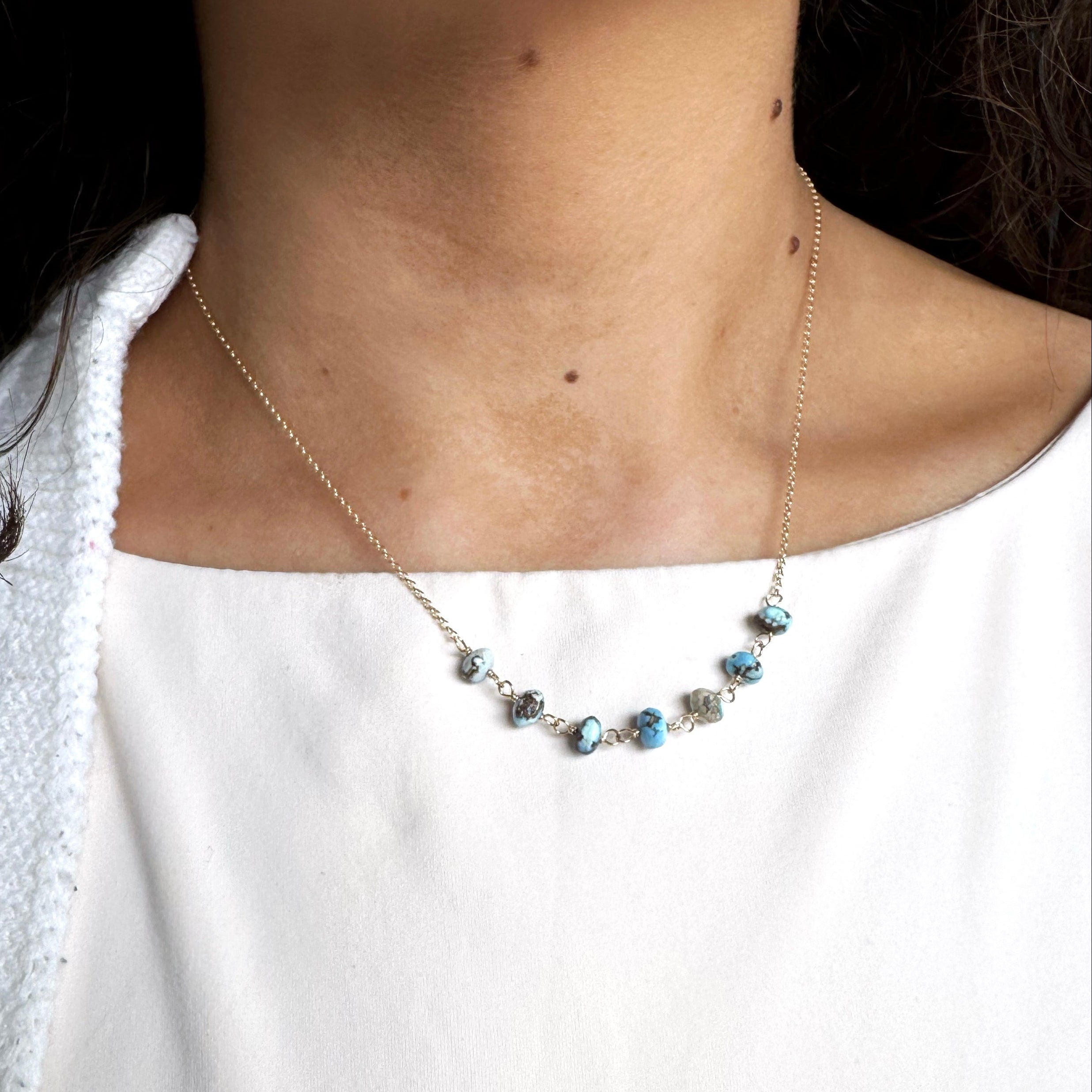 Necklace with small Golden Hill Turquoise beads worn by a person against a white background