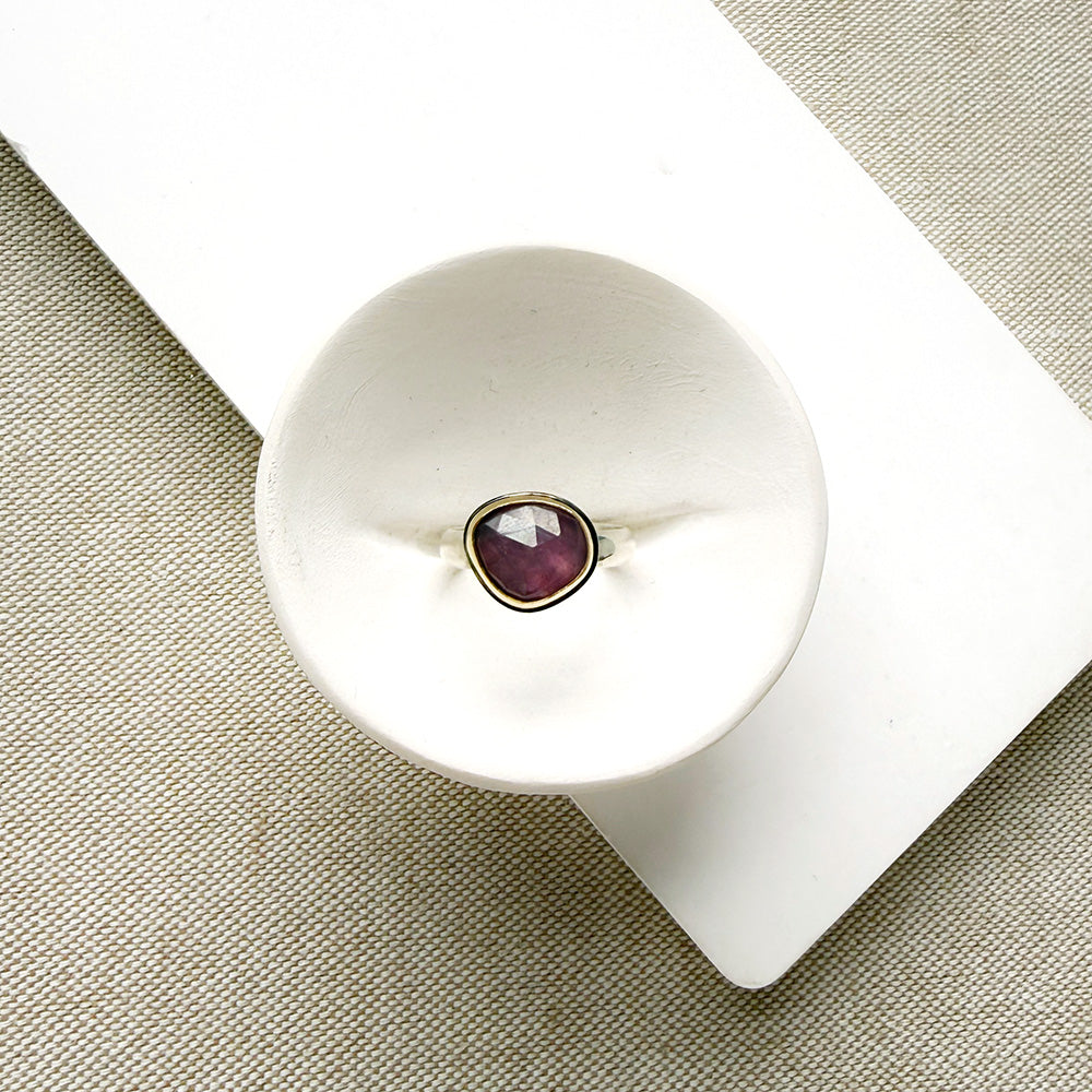 Rose cut pink sapphire mixed metal ring set in a white dish